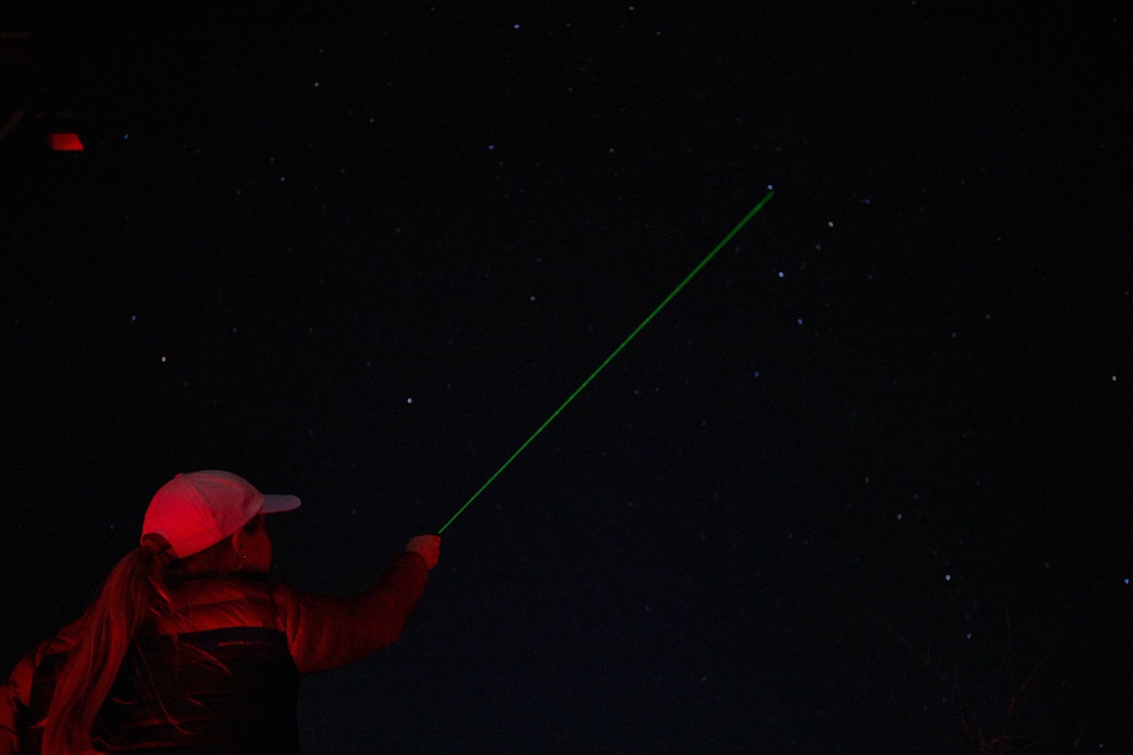 A stargazing guide pointing out constellations with a green laser under the night sky at Bryce Canyon
